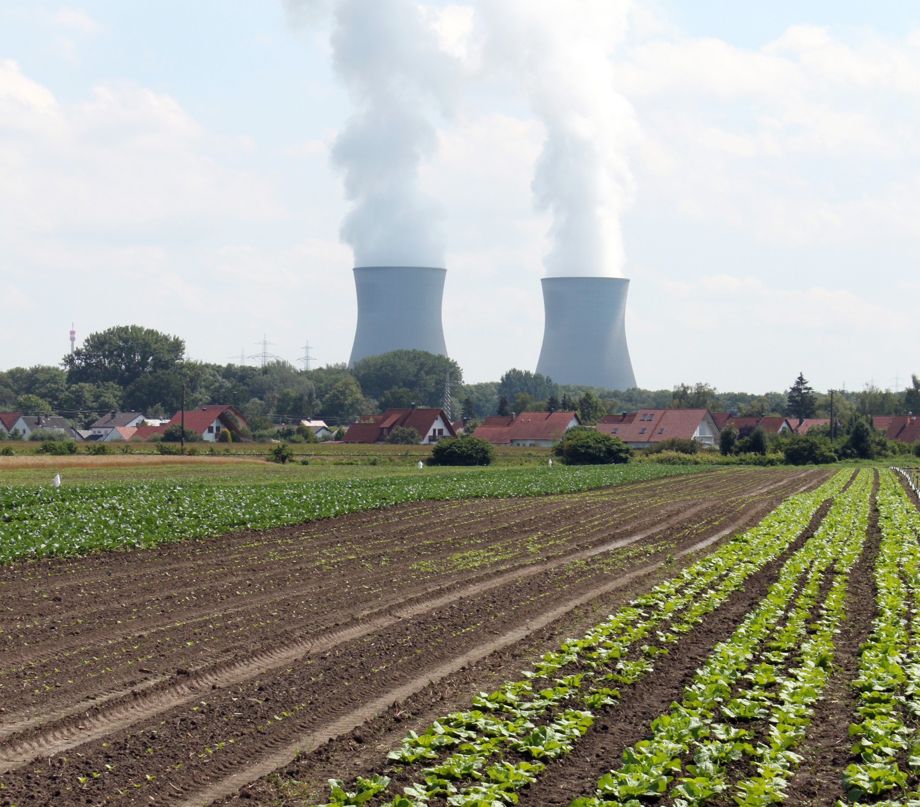 Ein bepflanzter Acker mit einem Kernkraftwerk im Hintergrund