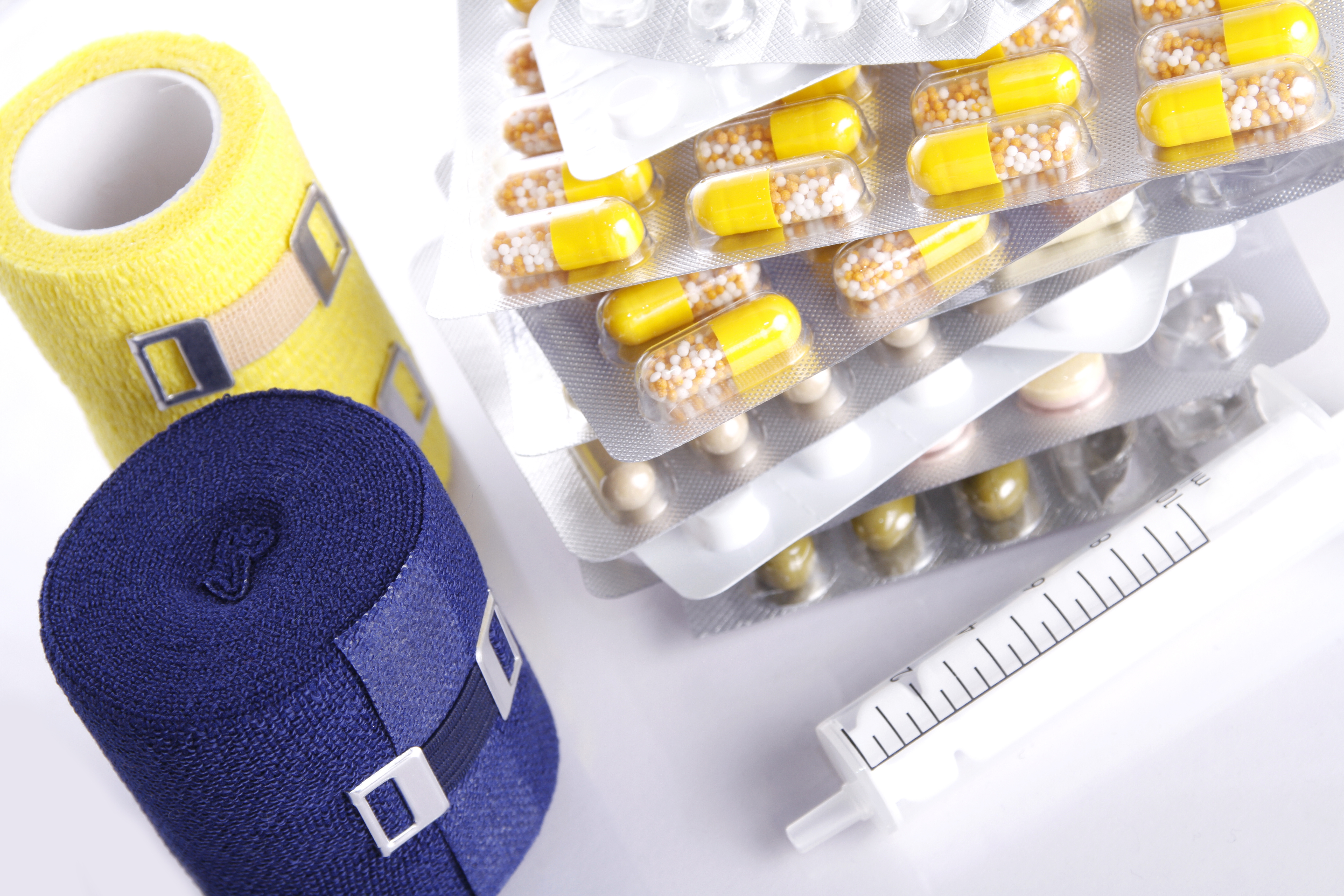 Bild mit Tablettenblistern und zwei Verbandsrollen in blau und gelb