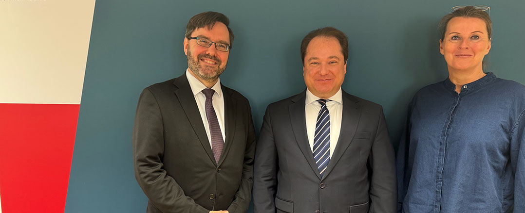 Bild: Dekoratives Bild (drei Personen stehen lächelnd vor einer Wand)